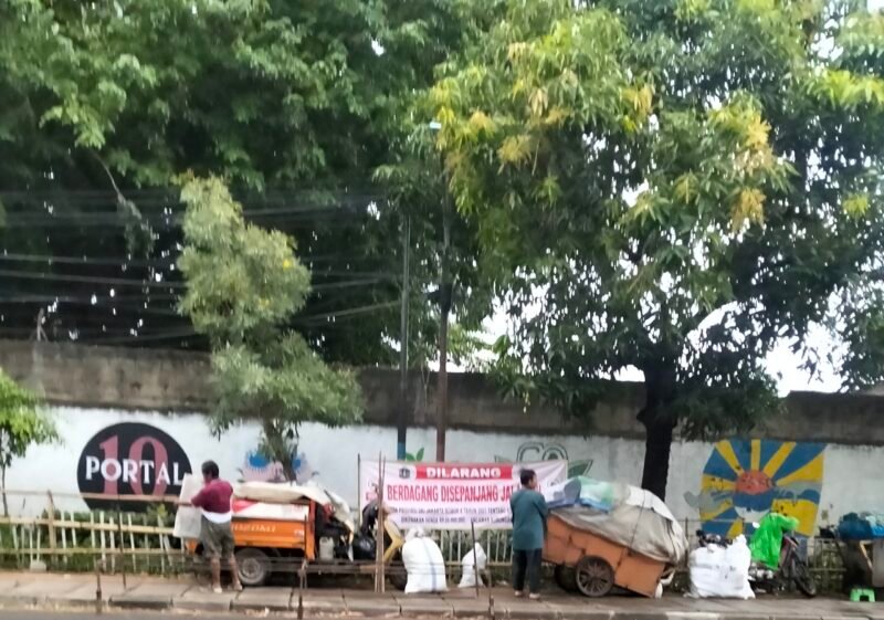 Pedagang di Jalan Kali Baru Timur Kapuk mulai menggelar dagangan di depan taman yang sudah di pasang spanduk larangan berjualan oleh pihak kelurahan kapuk 